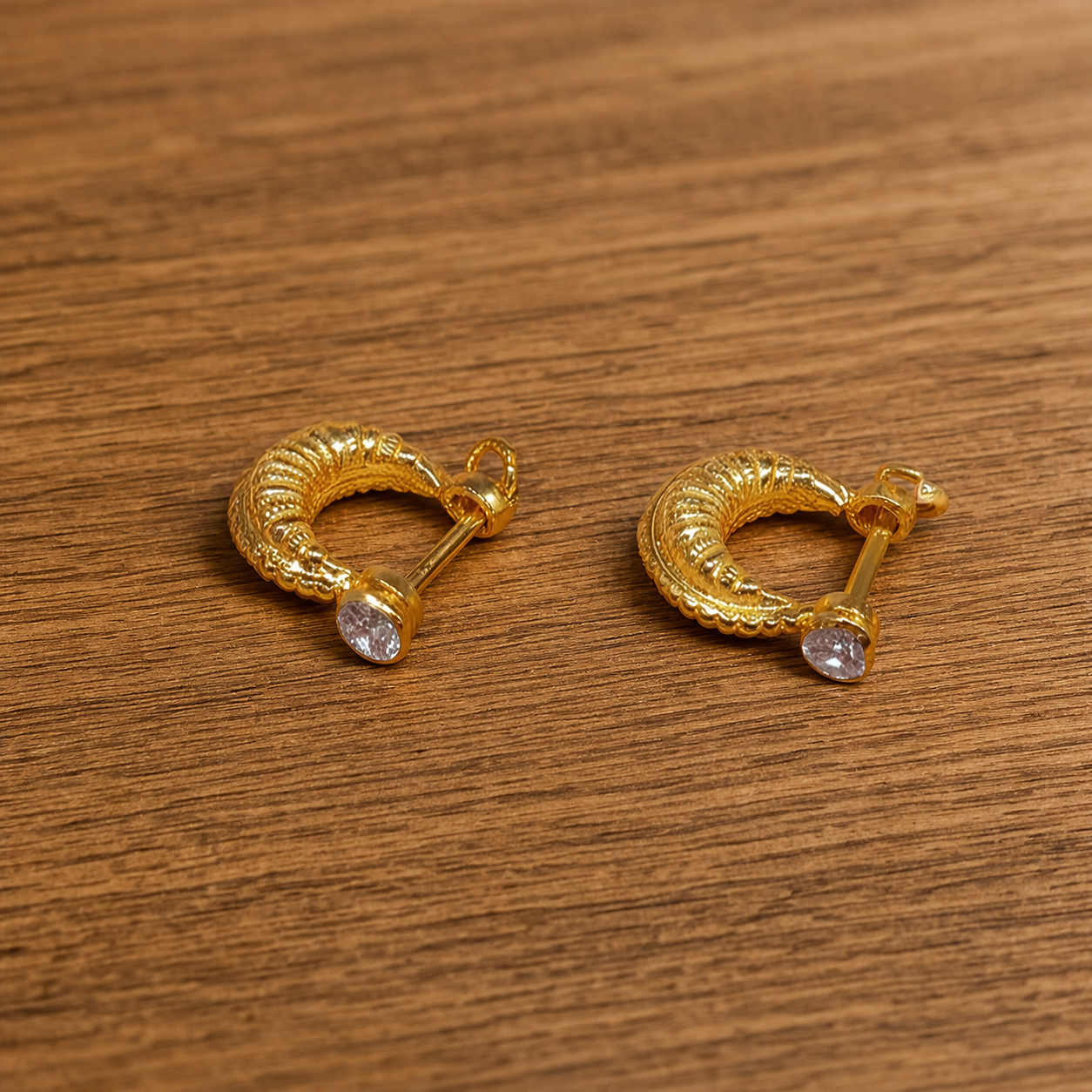 Gold earrings on a wooden surface Traditional Gents Murkiya Earring – Bold Ethnic Golden Style for Men (24K Gold)