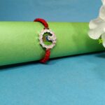 Pure Silver Krishna Rakhi with Green Enamel & Red Braided Thread