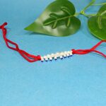 Elegant Pearl Beaded Rakhi with Blue Drops on Red Thread