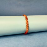 Surya Sutra Rakhi – Handwoven Orange Thread Rakhi with 925 Silver Beads